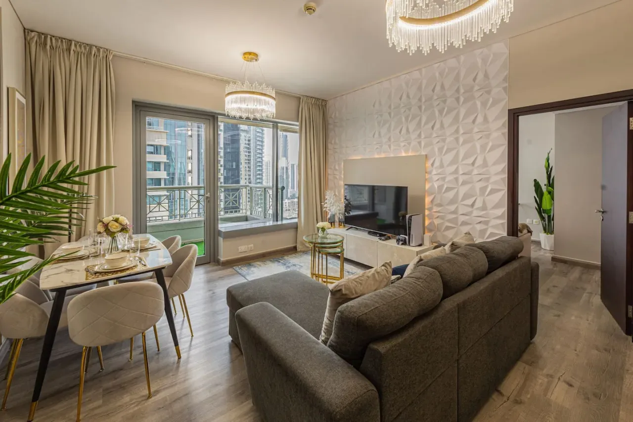 A living room with seating, a television, and large windows overlooking nearby buildings.