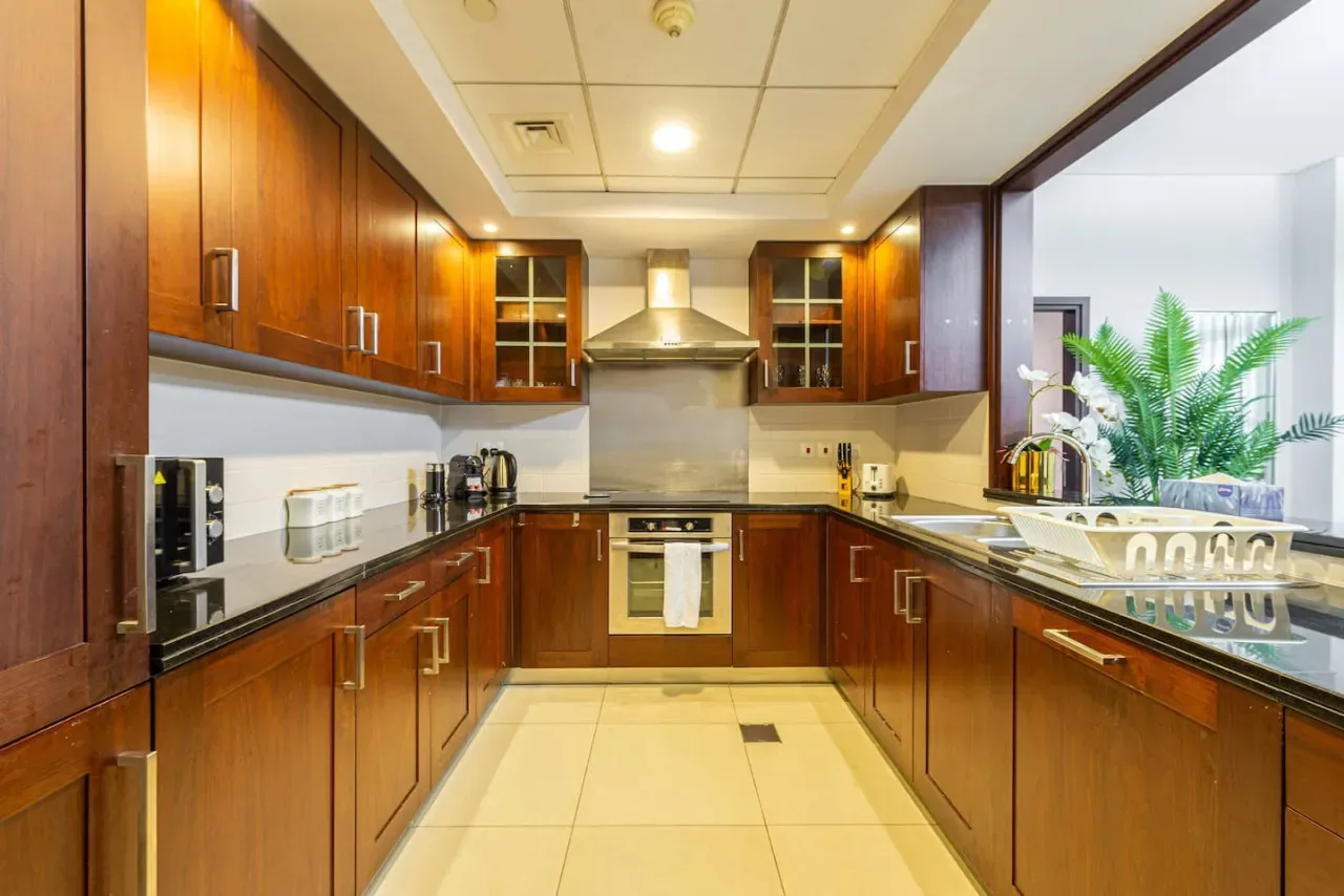 A warm-toned kitchen with wooden cabinets and an oven beneath a range hood.