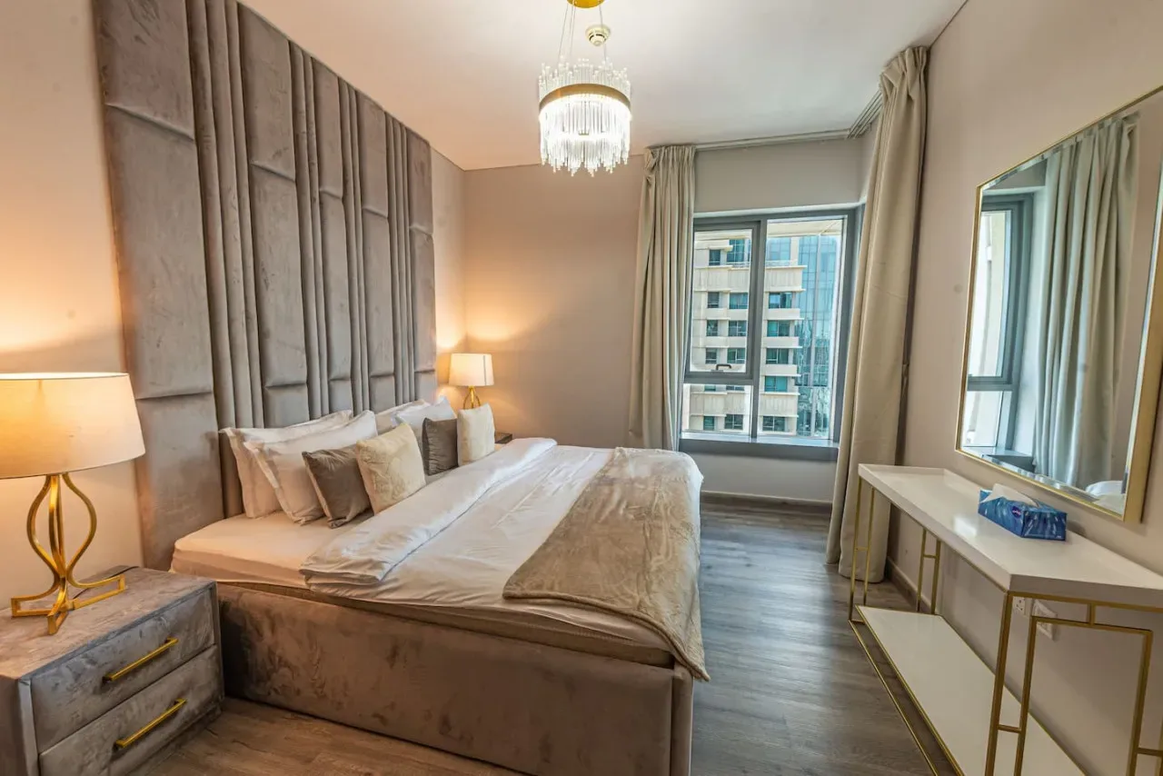 A bedroom with a large bed, bedside lamps, and a window.