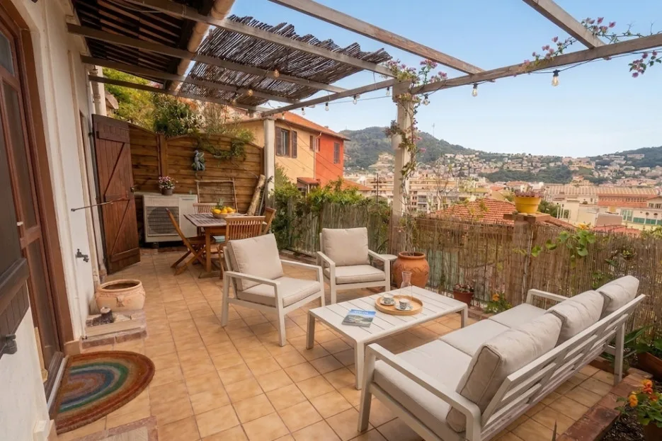A furnished terrace with outdoor seating and a view of the surrounding hillside.
