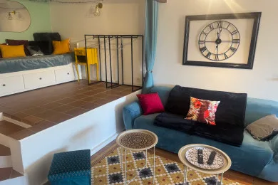 A living room with a dark sofa, patterned cushions, and two small round tables.