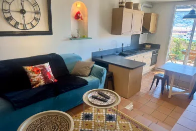 A living area with a dark sofa beside an open kitchen and dining table.