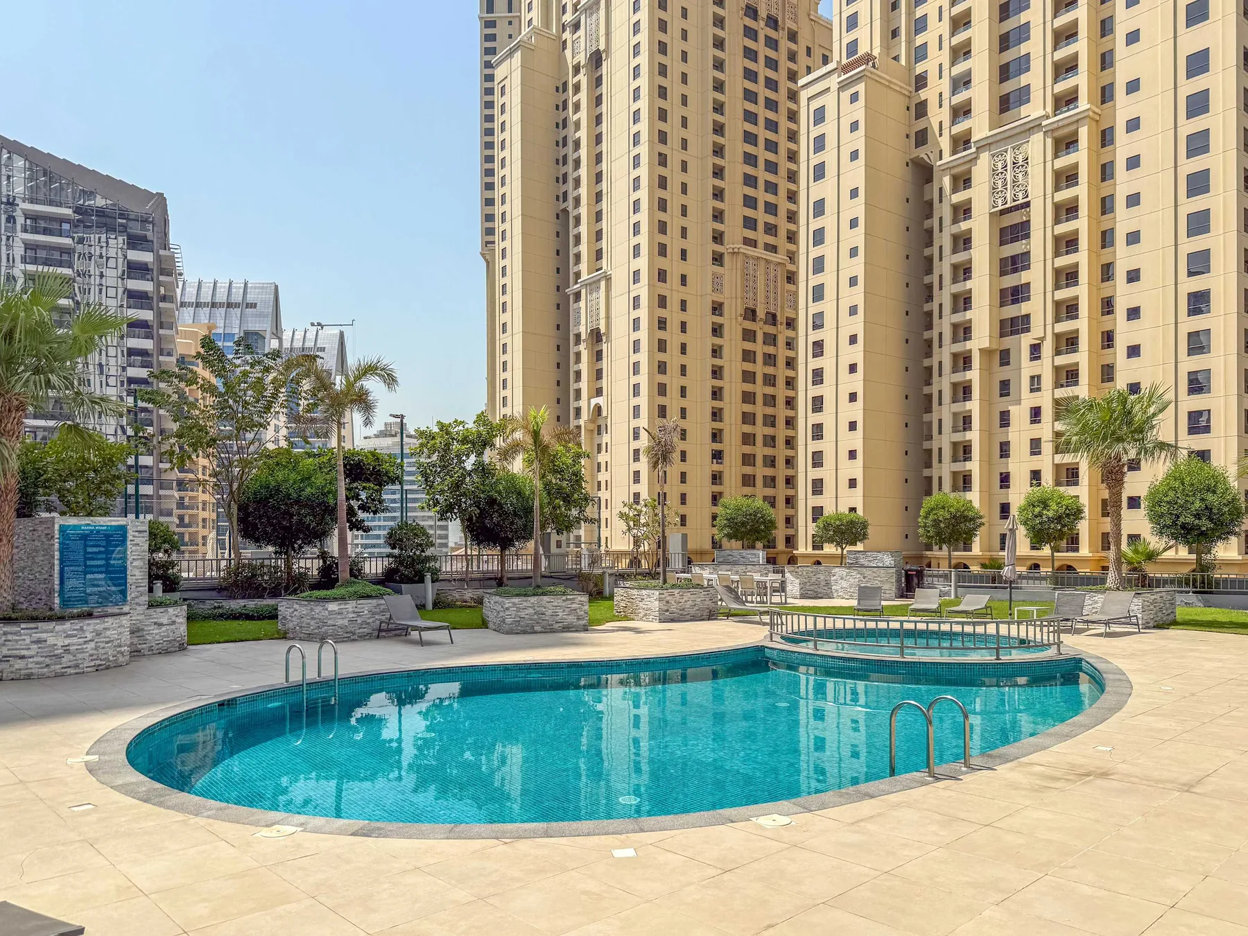 Una piscina exterior curva se encuentra entre edificios residenciales altos.