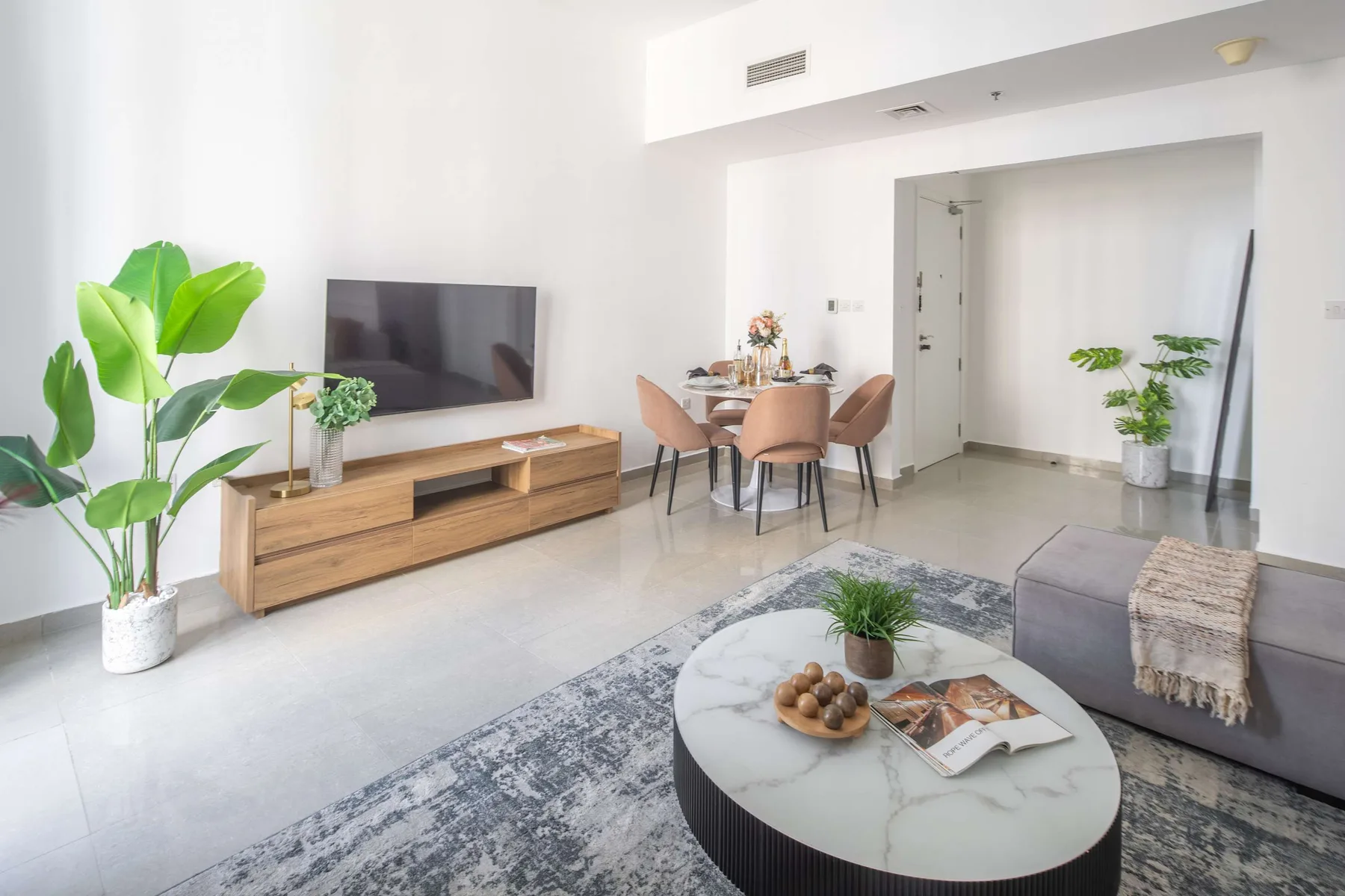 Una sala luminosa con televisor, mesa de comedor y mesa de centro.