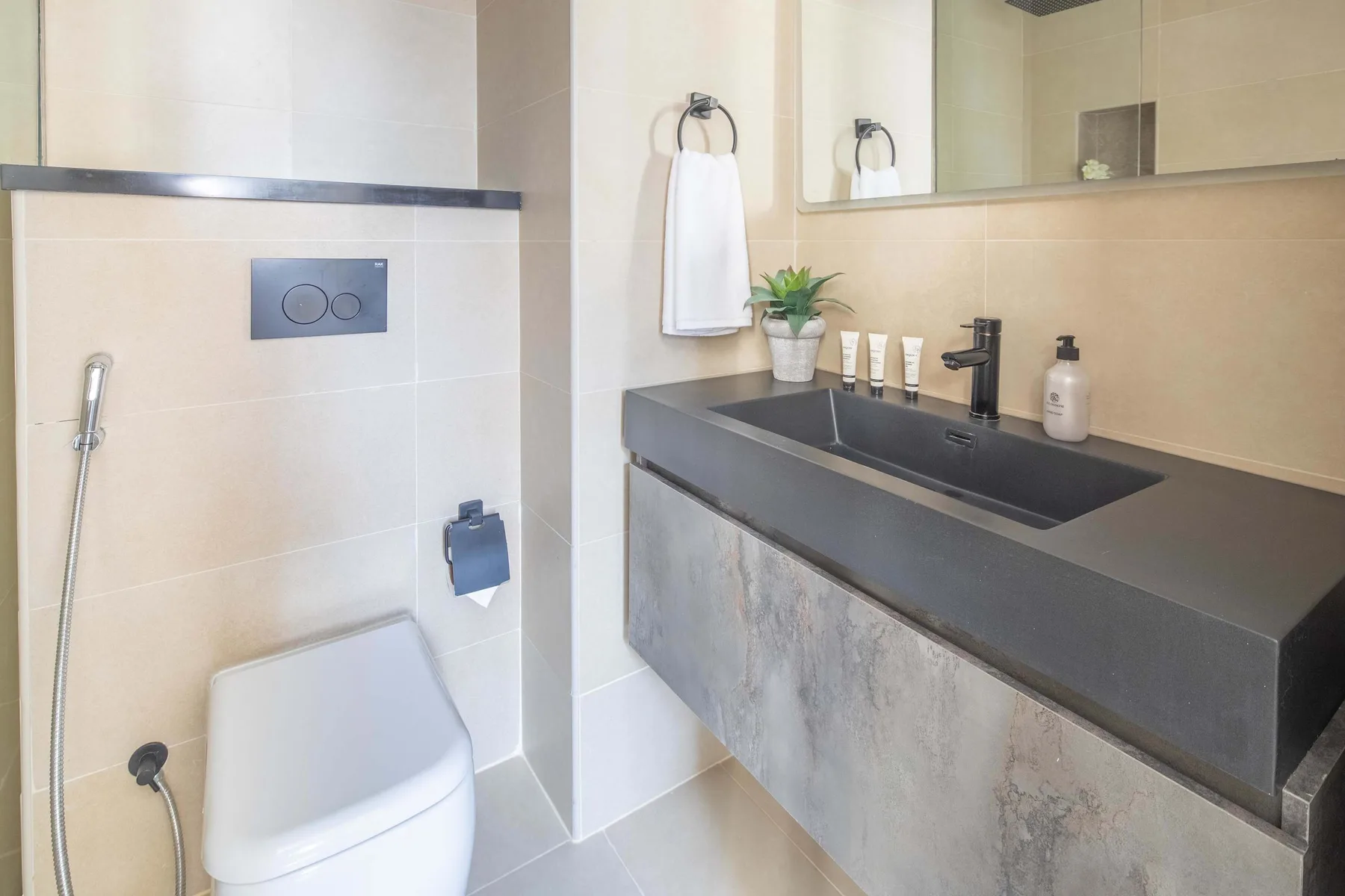 Un baño con un inodoro y un largo lavabo bajo un espejo.