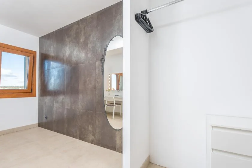 A bright room with a large dark tiled wall and a window.