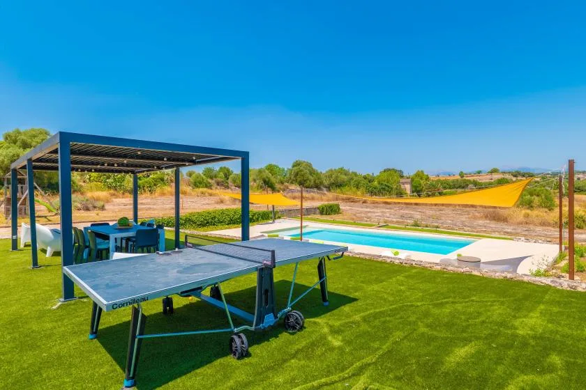 An outdoor recreation area with a table tennis table and swimming pool.