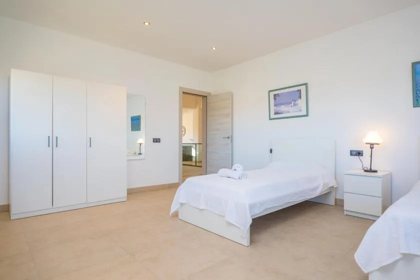 A bright bedroom with a bed, wardrobe, and bedside table.