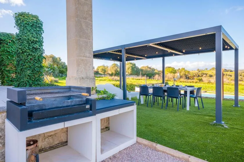 An outdoor dining area with a table and seating beneath a covered pergola.