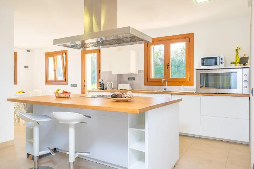 A bright kitchen with a central island and wooden-framed windows.