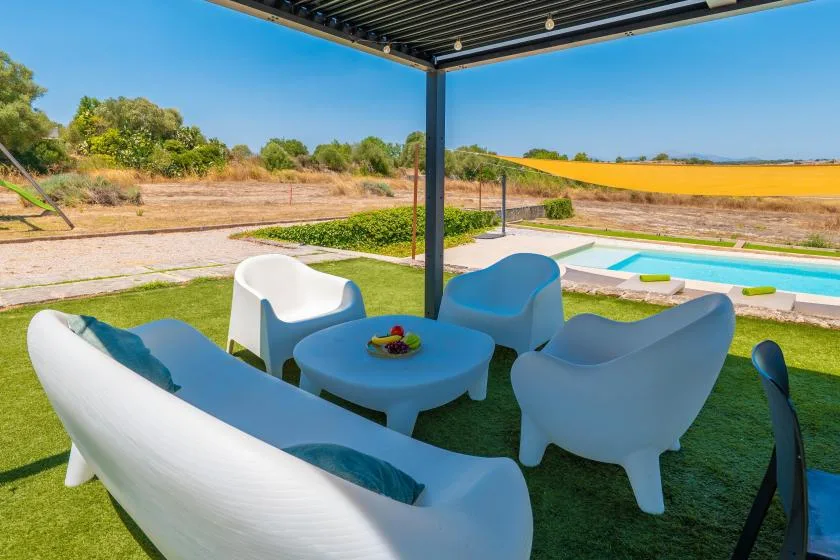 A shaded outdoor seating area overlooks a swimming pool and dry landscape.