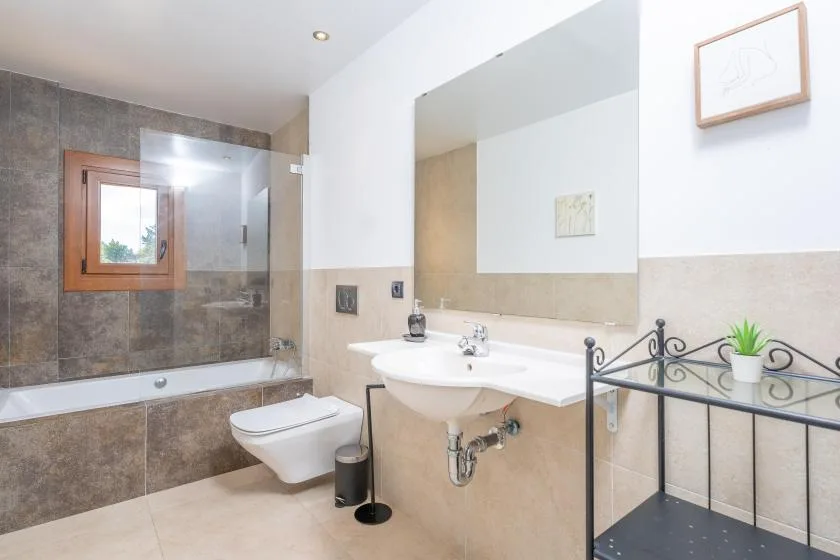A bathroom with a bathtub, toilet, and sink beneath a large mirror.