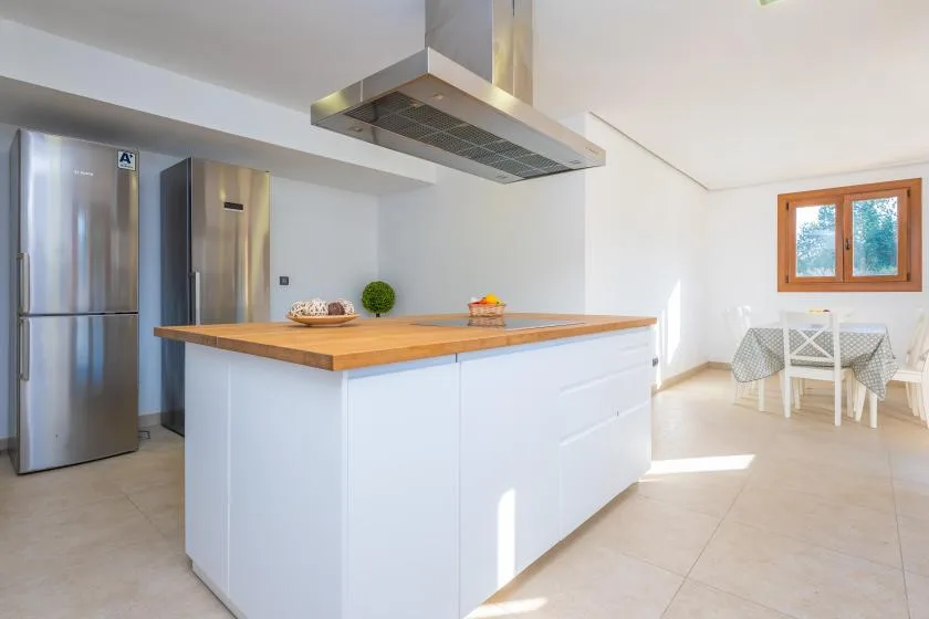 A bright kitchen with a large island and a small dining table by the window.