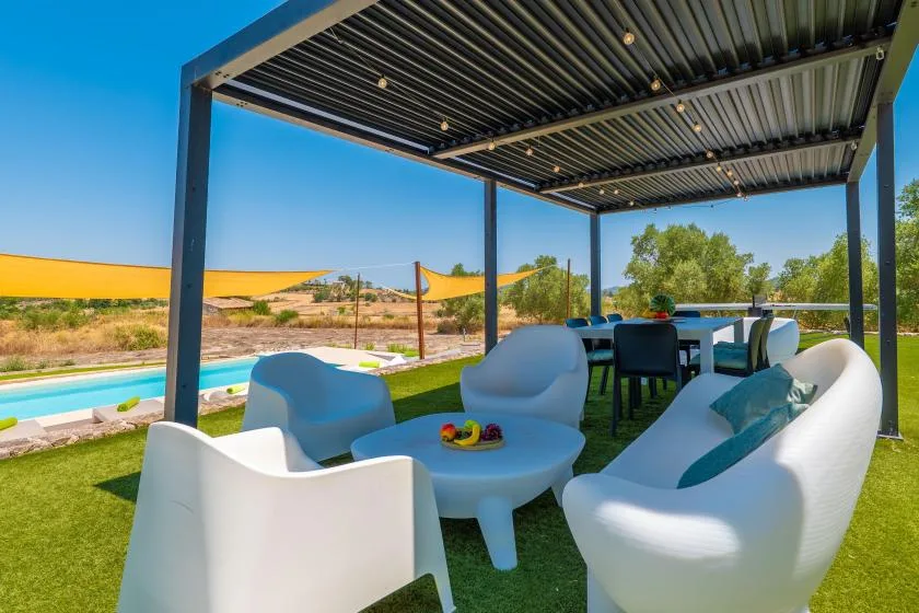A covered outdoor seating area overlooks a swimming pool and landscaped grounds.