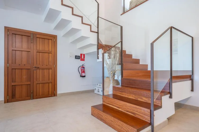 A bright interior entryway with a wooden staircase and double doors.