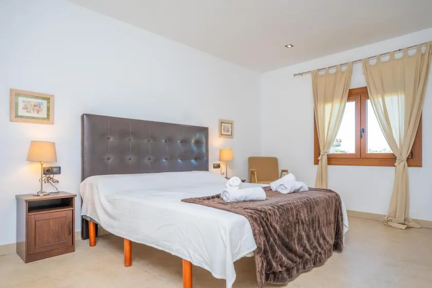 A bedroom with a large bed, bedside tables, and curtains by the window.