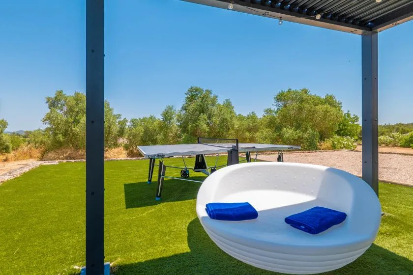 A covered outdoor seating area overlooks a green lawn and a table tennis table.
