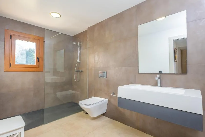 A modern bathroom with a glass shower, toilet, and wall-mounted sink.