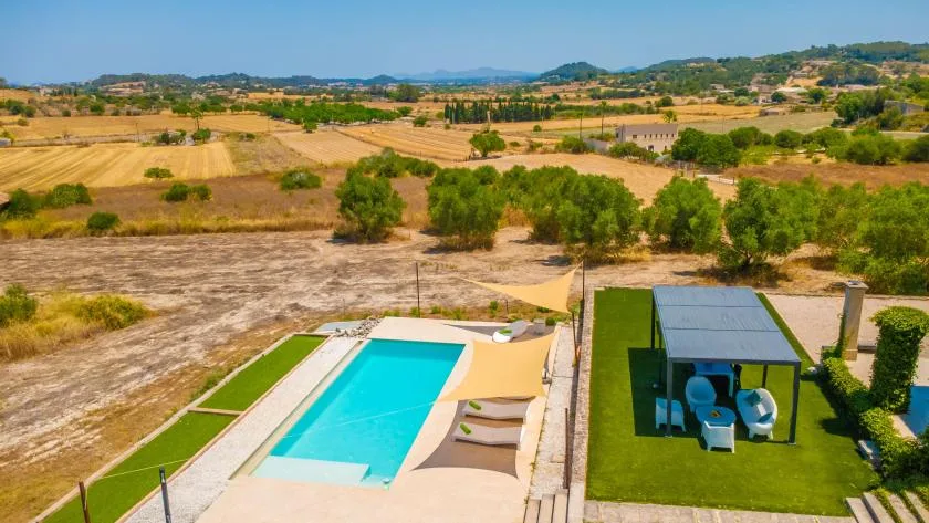 A swimming pool and shaded seating area overlook a dry rural landscape.