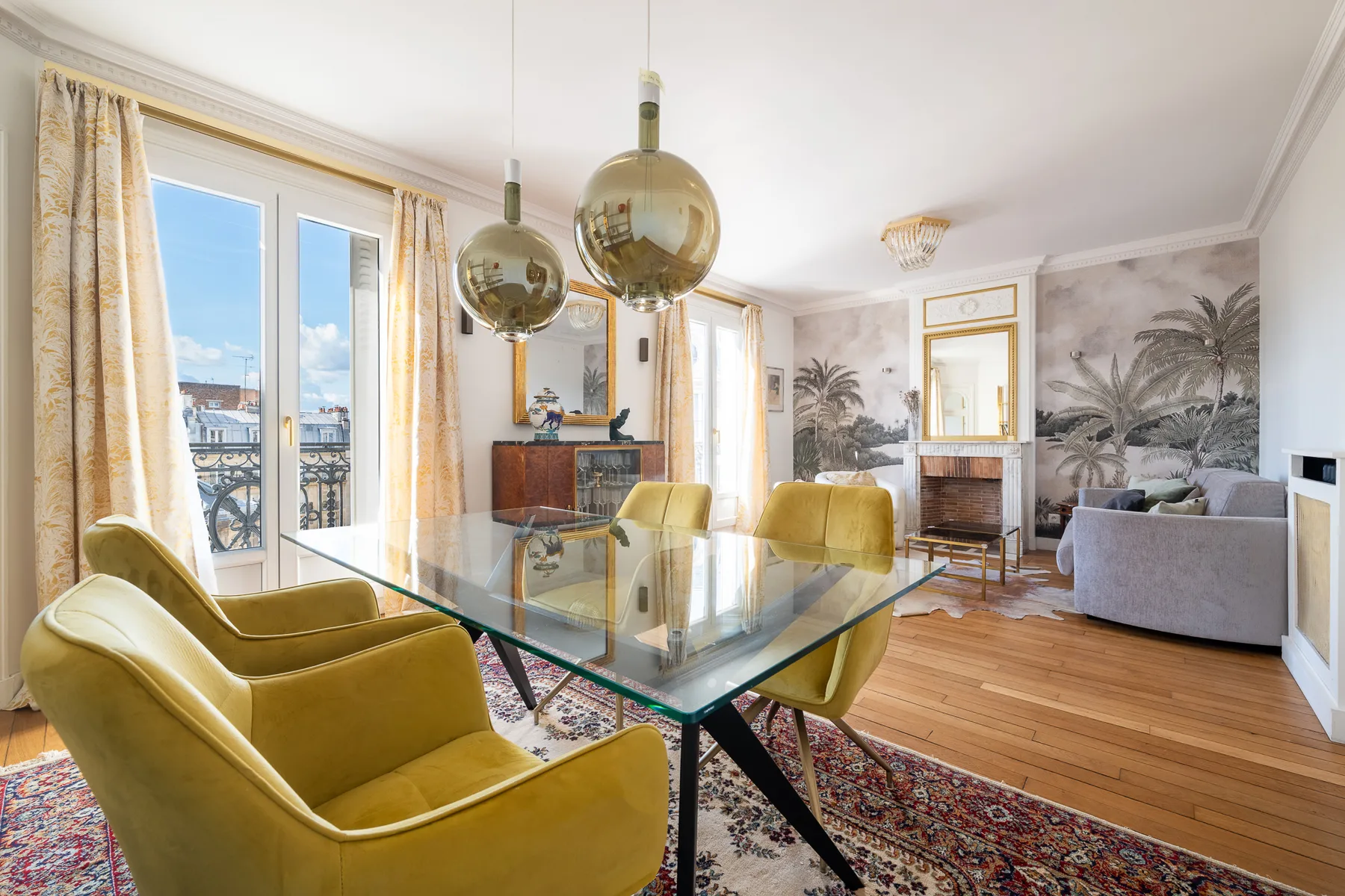 A bright living and dining room with yellow seating and a glass dining table.