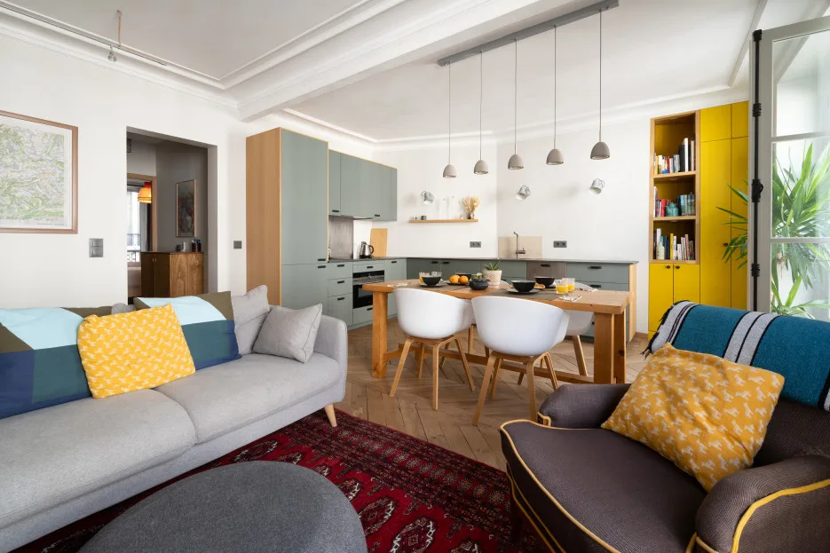 Una luminosa sala de estar y comedor con asientos, una mesa y una cocina.
