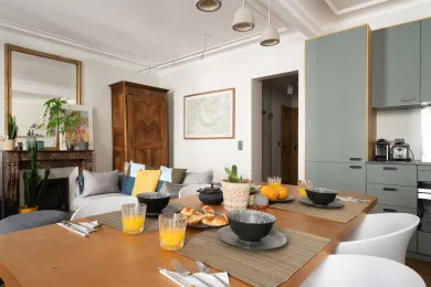 A dining area with a wooden table set with dishes beside a living space.