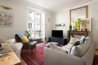 A bright living room with seating, a television, and a patterned rug.