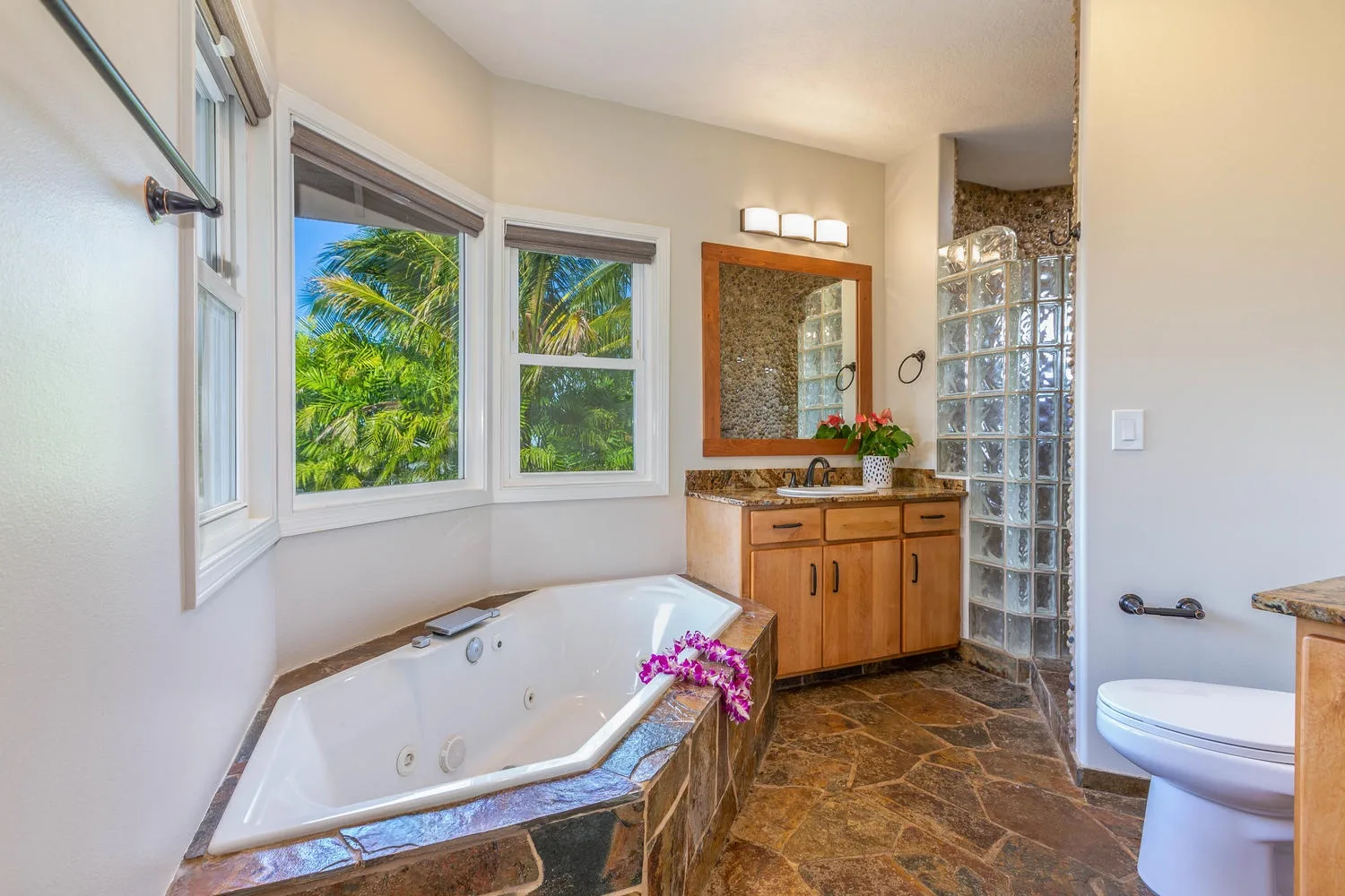 A bathroom with a bathtub, vanity, and windows overlooking greenery.