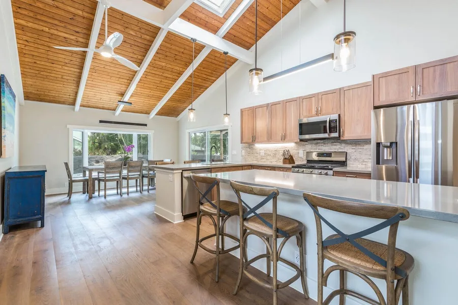 An open kitchen and dining area with a breakfast counter and exposed wood ceiling.