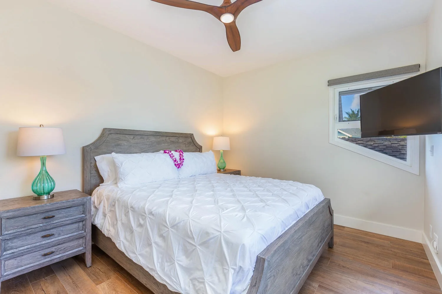 A bedroom with a large bed, bedside tables, and a wall-mounted television.
