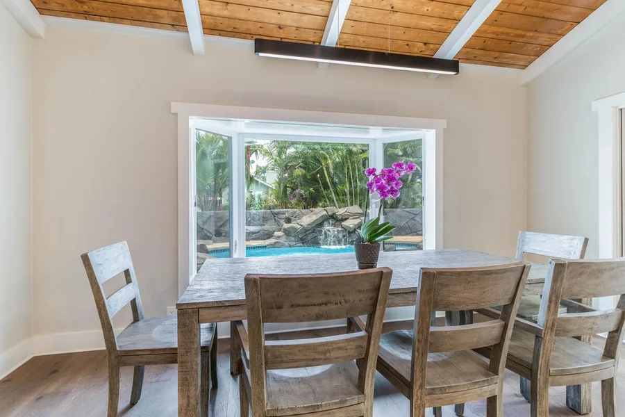 A dining area with a wooden table and chairs beside a large window.