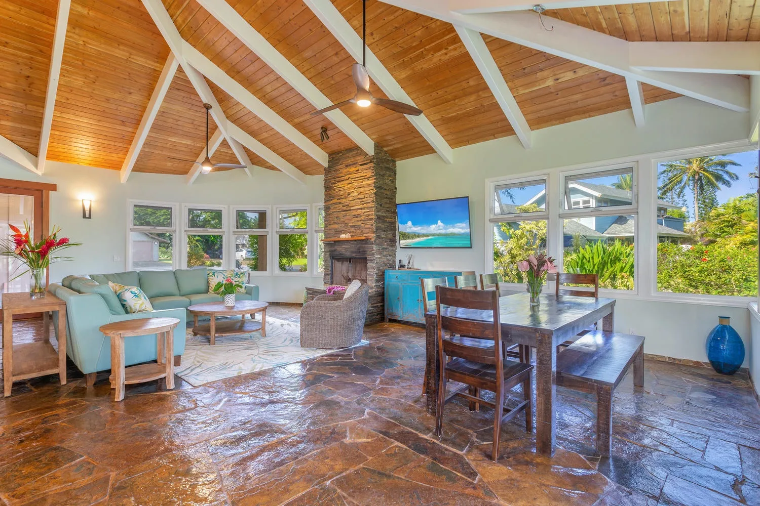 An open living and dining room with a high timber ceiling and broad windows.