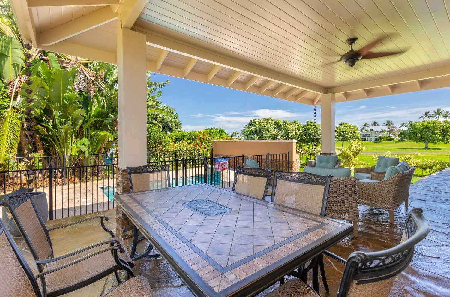 A covered outdoor dining area overlooks a pool and landscaped grounds.
