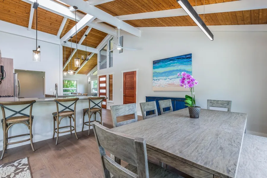 A dining area with a large table, chairs, and colorful wall art.