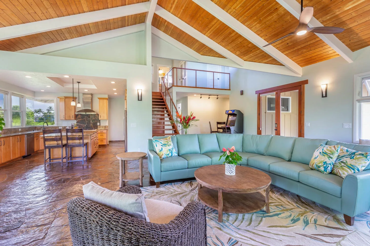 An open living room with a pale sectional, coffee table, and kitchen area.