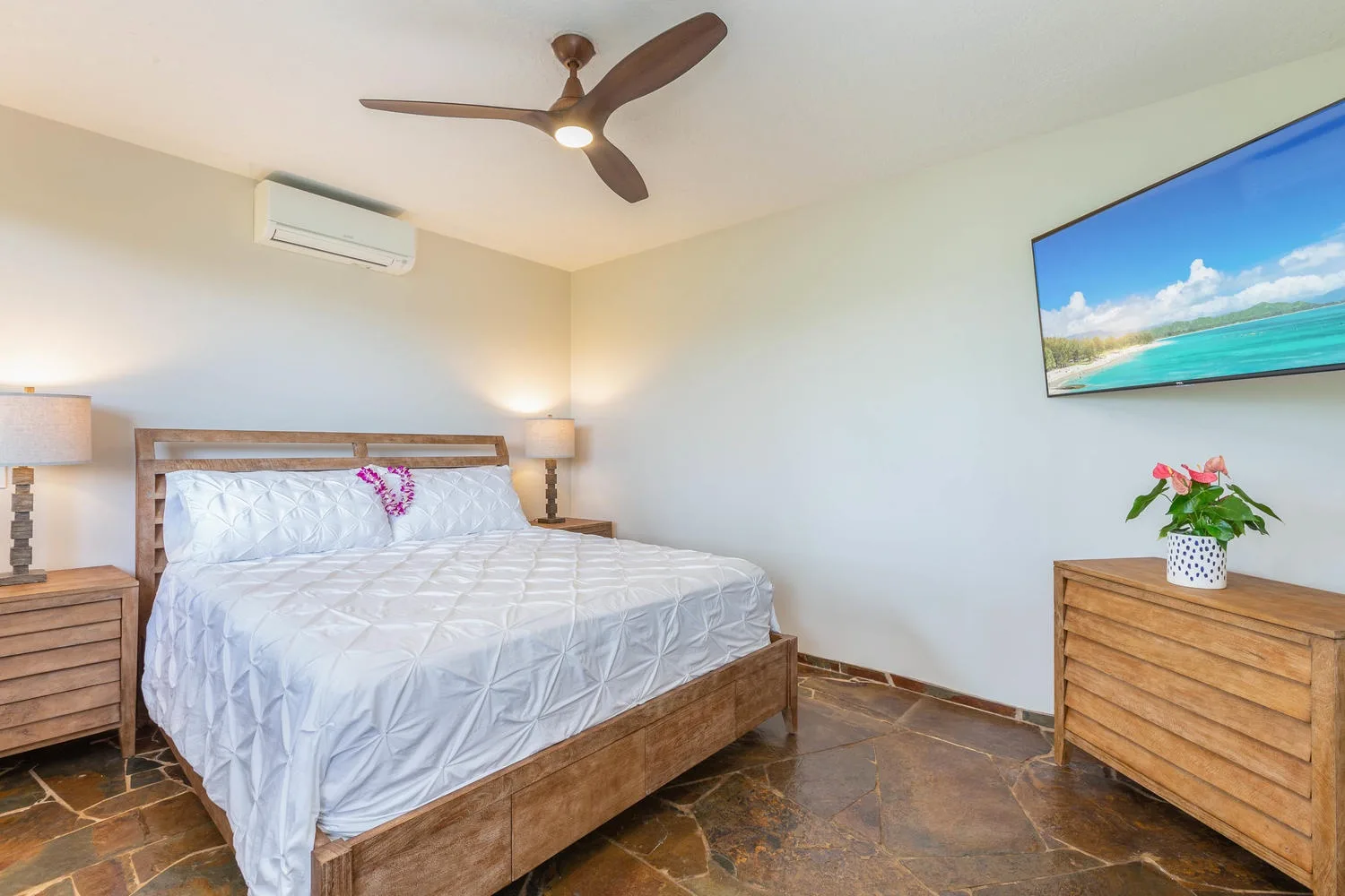A bedroom with a wooden bed, bedside tables, and a wall-mounted television.