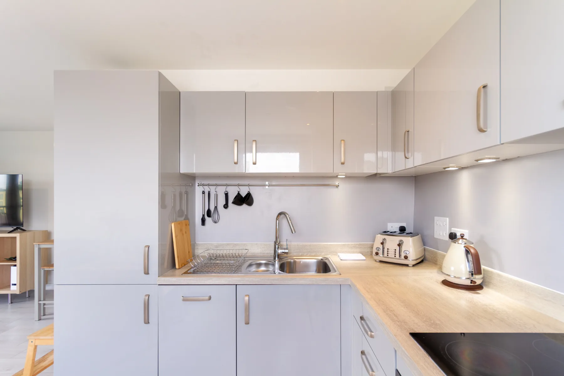 Una cocina luminosa con gabinetes claros, un fregadero y una encimera de madera.