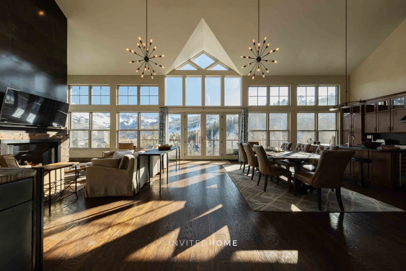 A spacious living and dining area with large windows and sunlight across the floor.