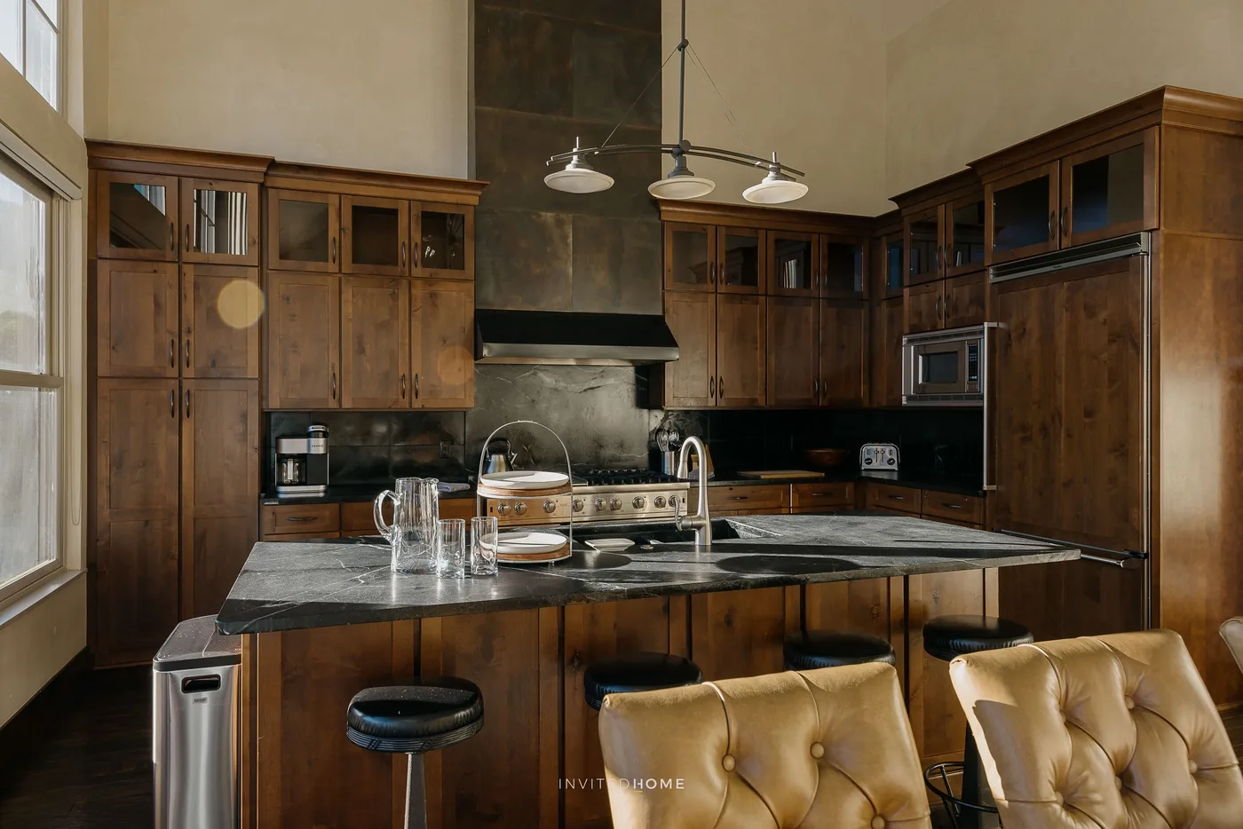 A spacious kitchen with dark wood cabinets, a central island, and pendant lights.