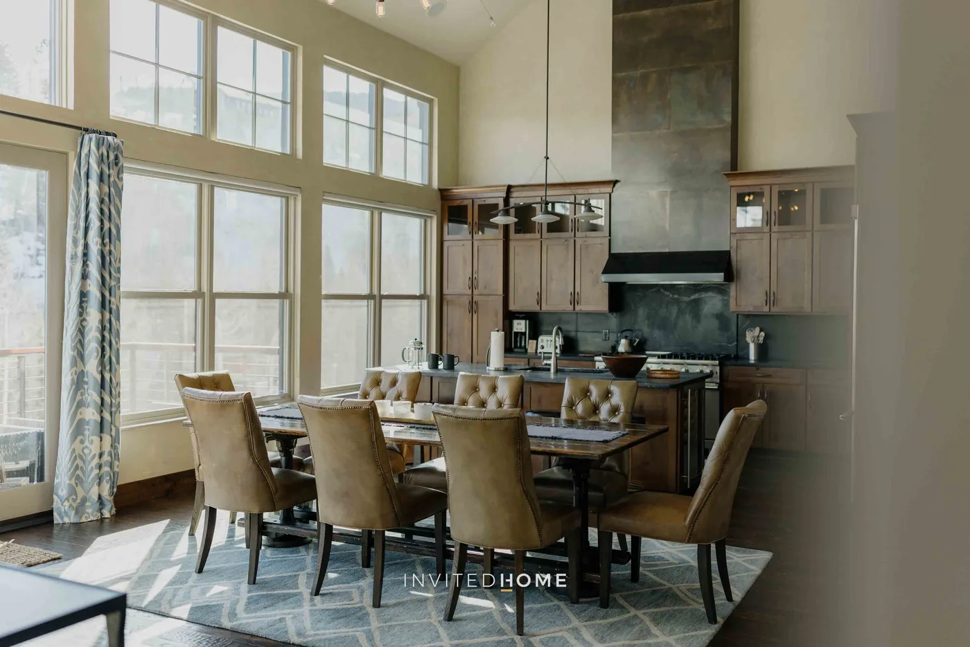 A dining area with a long table and large windows.