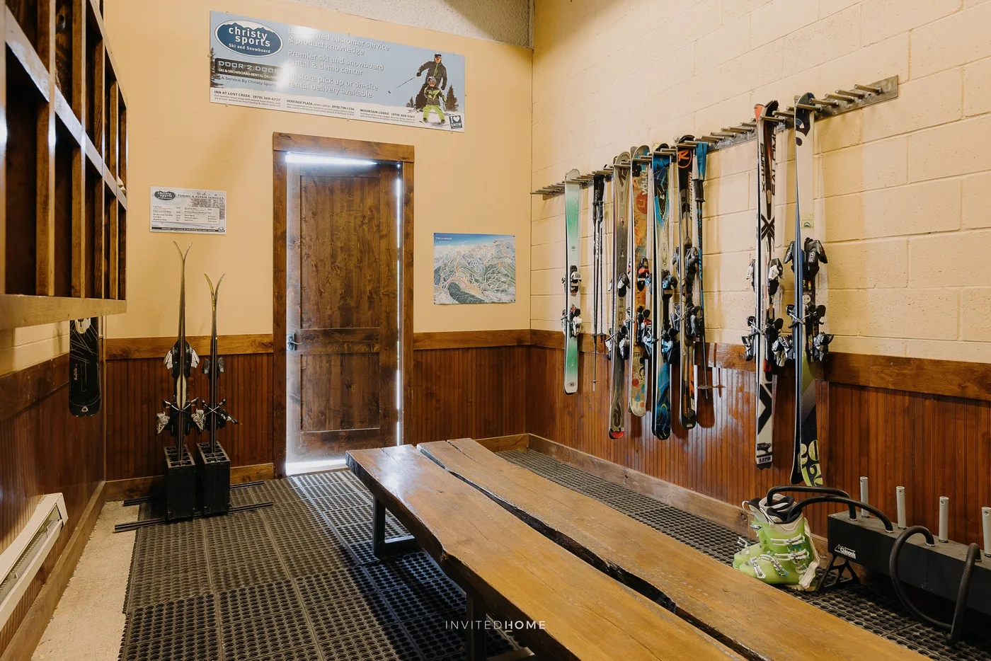 A ski equipment room with skis and poles stored along the walls.