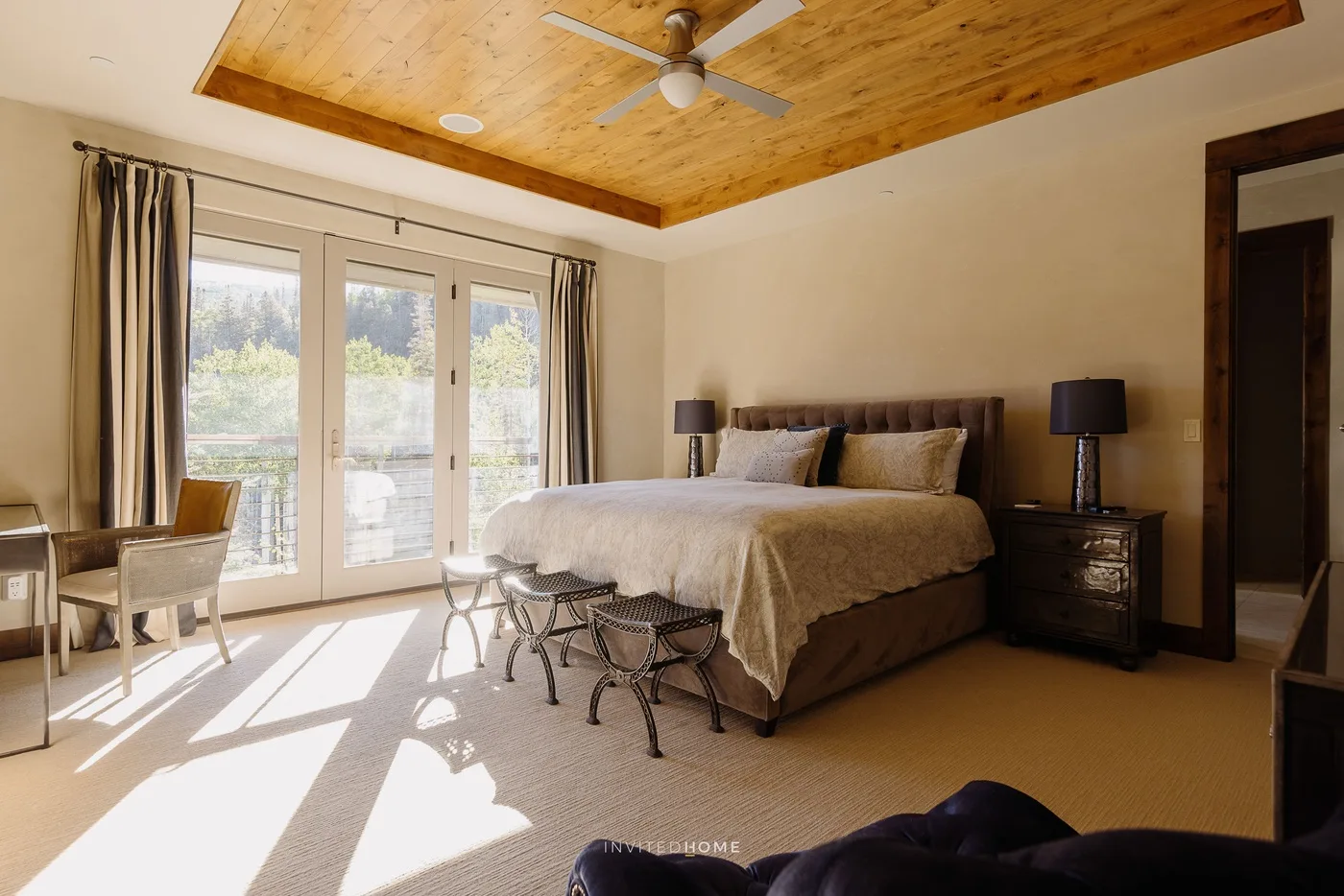 A bright bedroom with a bed, bedside tables, and glass doors opening onto a balcony.