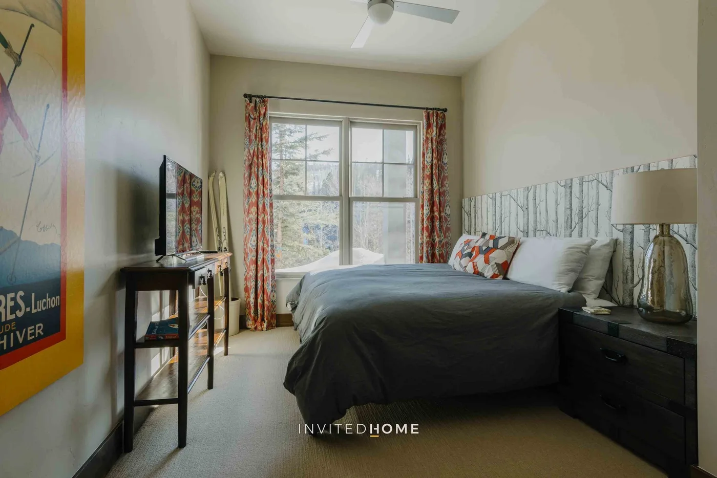 A bedroom with a bed, a window, and patterned curtains.