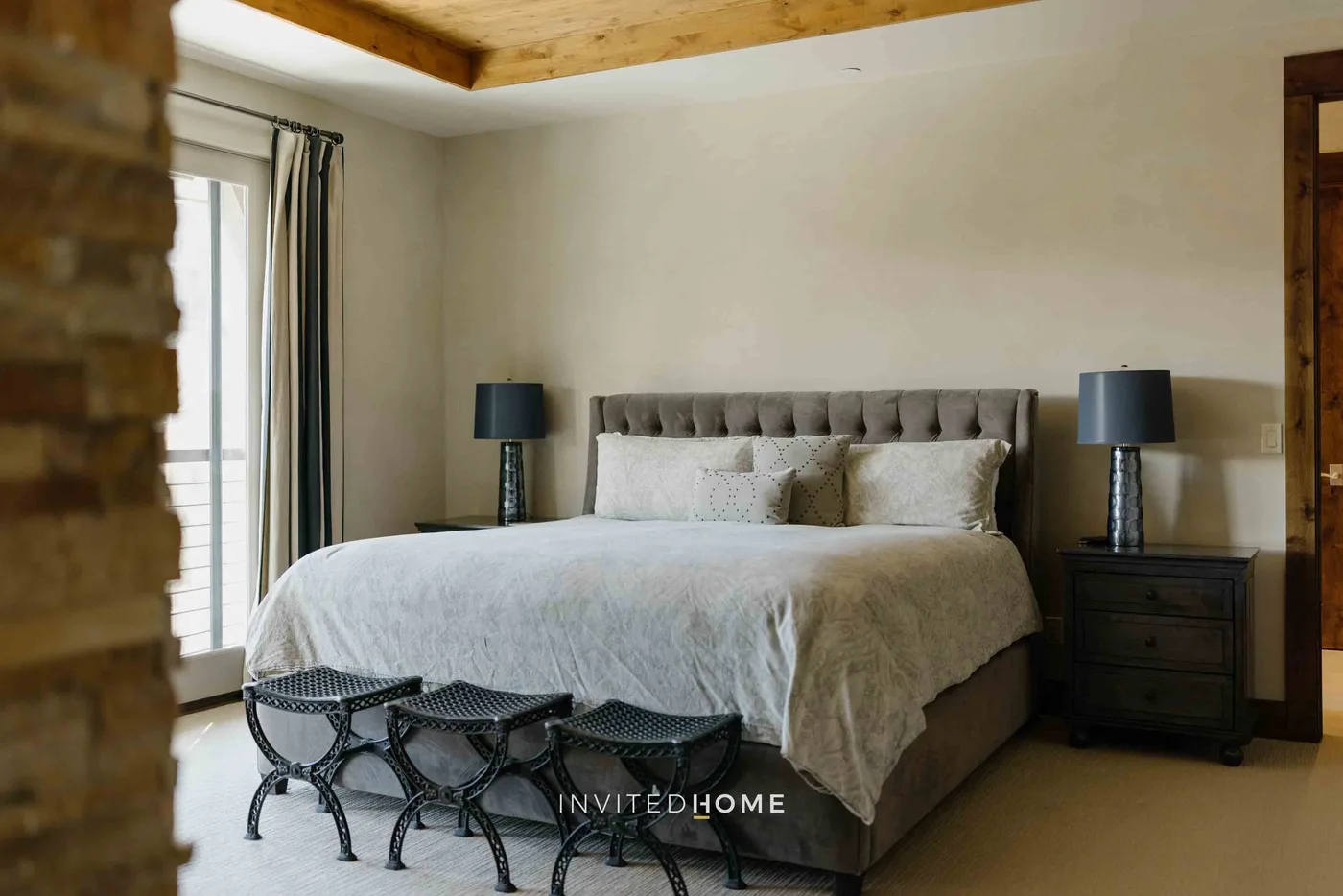 A bedroom with a large bed, bedside tables, and seating at the foot.