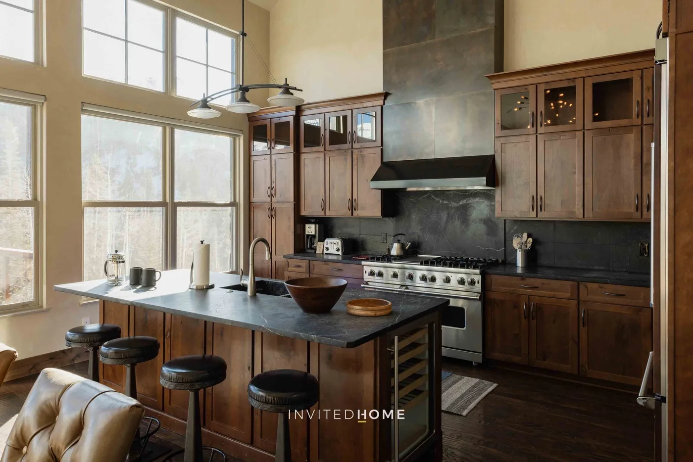 A spacious kitchen with a central island, dark cabinetry, and large windows.