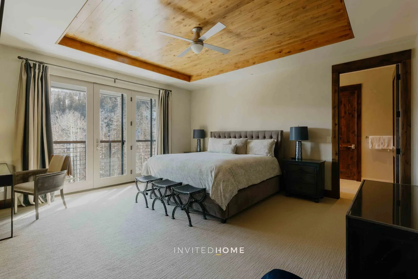 A bedroom with a large bed, bedside tables, and tall windows.