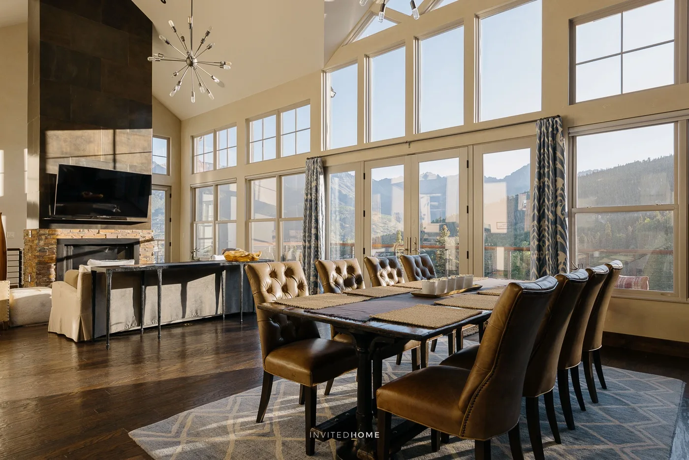 A spacious dining and living area features large windows and a long dining table.