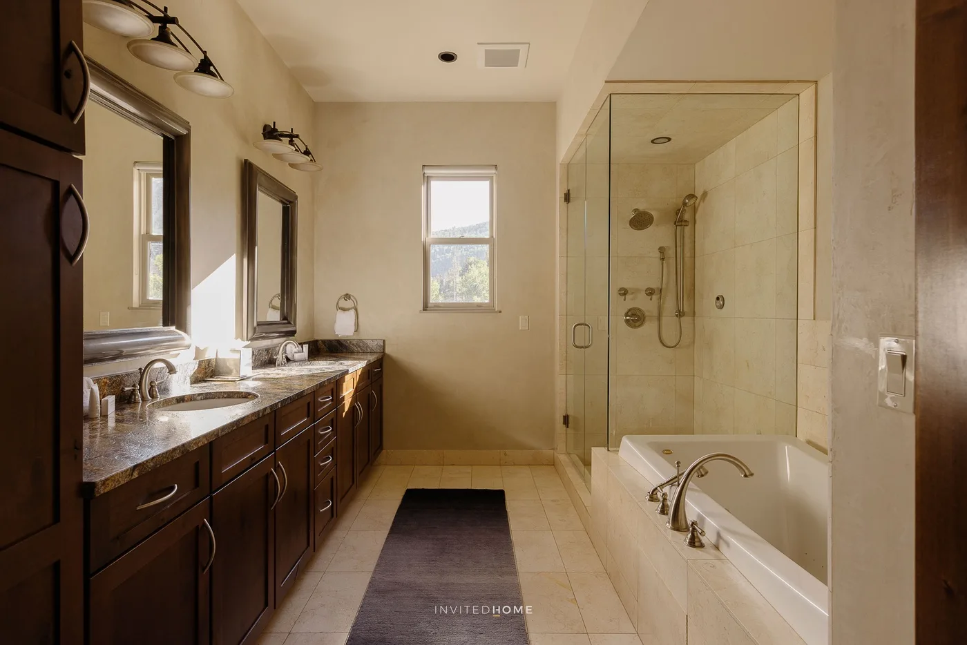 A bathroom with a long vanity, bathtub, and glass-enclosed shower.
