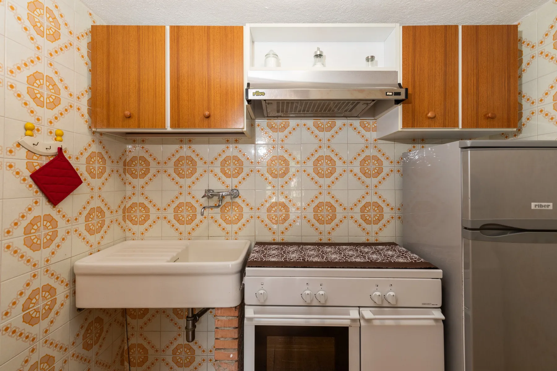 A kitchen with patterned tile, wooden cabinets, and a stove.