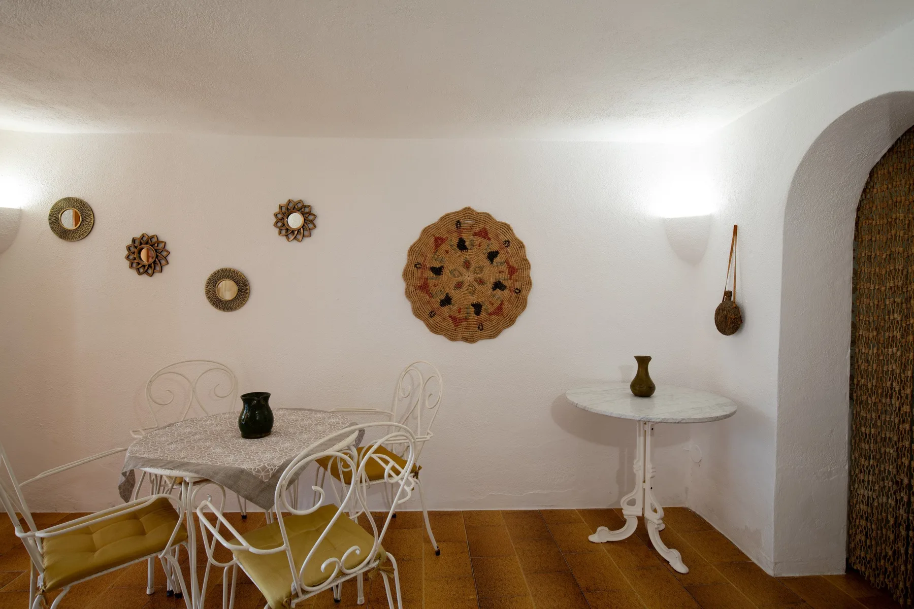 A dining area with metal seating, a round table, and decorative wall hangings.
